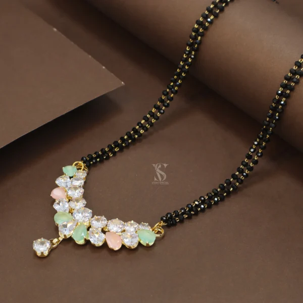 Introducing an extremely attractive and fashionable 36-inch Mangalsutra! This Mangalsutra is made from high-quality alloy, giving it a special and modern look. Its pendant features attractively set fancy colored stones, making it stand out even more. Two strands of black crystal beads are attached to this pendant, further enhancing the beauty of this Mangalsutra. A small dangling stone at the bottom adds to its charm. Its 36-inch length allows it to be worn in various ways and it looks beautiful with any modern attire. This Mangalsutra is lightweight, making it excellent for everyday wear as well. The fancy design and the shine of the attractive colored stones, along with the black crystal beads, give this Mangalsutra a special and stylish look, creating a distinct identity for your personality. Key Features: Modern Fancy Design: Attractive and trendy look. Attractive Colored Stones: Charming and eye-catching stones. Black Crystal Beads Strands: Gives the design a special and unique touch. High-Quality Alloy: Durable and attractive. 36 Inch Length: Convenient and stylish for various wearing styles. Lightweight: Comfortable for everyday wear. Excellent for Modern Attire: Fashionable and attractive. This fancy colored stone and black crystal beads 36-inch long Mangalsutra will definitely complete your modern and stylish look!