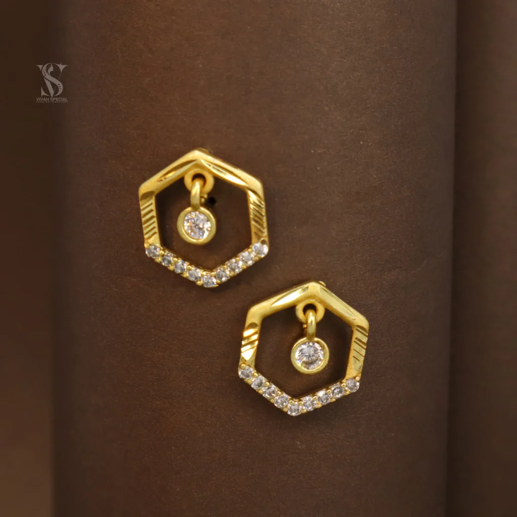 Presenting charming hexagonal-shaped gold plated stud earrings adorned with white stones! These earrings are specially designed for your modern and unique look. The gold plated frame in a hexagonal shape and the sparkling white stones set on the lower side give these earrings a special and attractive look. Also, a small dangling white stone in the center further enhances their beauty. These earrings are made from high-quality material and have a beautiful gold plating, making them look extremely attractive and premium. The stud design makes them easy and comfortable to wear. The special thing about these earrings is their unique hexagonal design and the shine of the white stones, which will give you a distinct and stylish look for any special occasion or everyday wear. They add to your beauty and give you a confident personality. Key Features: Unique Hexagonal Design: Attractive and distinct look. Sparkling White Stones: Beautiful and charming shine. Gold Plated: Beautiful and durable golden shine. Stud Design: Easy and comfortable to wear. High-Quality Material: Durable and safe. Suitable for Everyday and Special Occasions: Excellent choice for any time. Excellent Gift: A beautiful and stylish gift for your loved ones. Give a special touch to your beauty with these attractive hexagonal design white stone gold plated stud earrings!